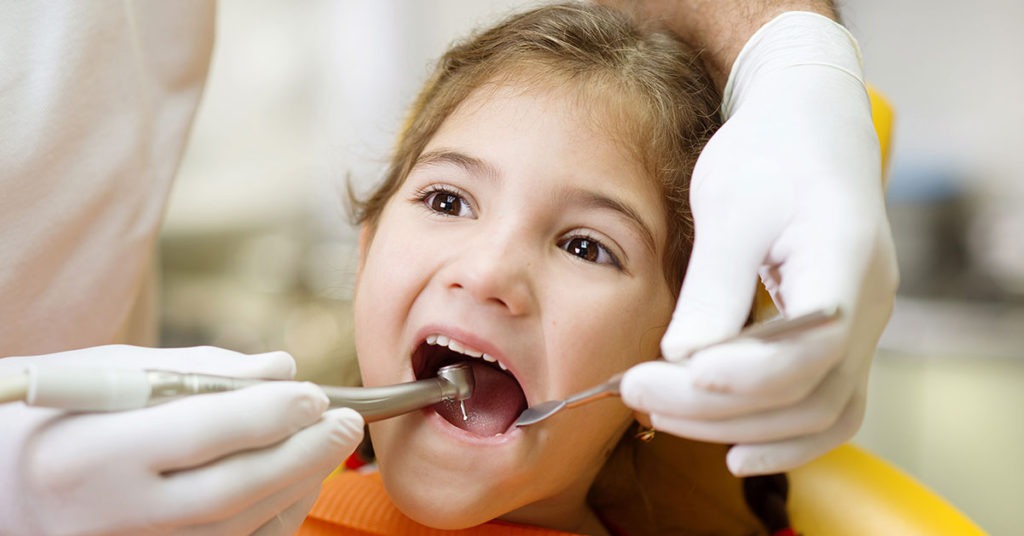 Dentist examining decayed milk teeth of child